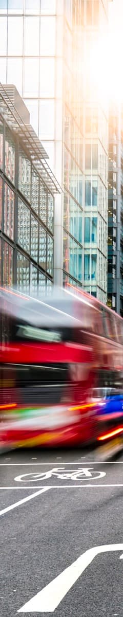 A red double-decker bus passing through a London street
